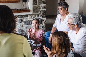 Hispanic family playing domino game with grandmother and daughter at home, three generations of women in Mexico Latin America	