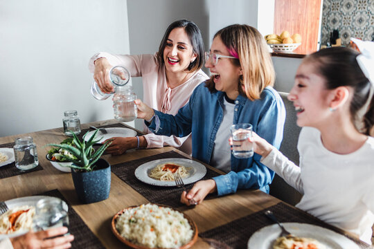 Hispanic Mother And Teenager Daughter Smiling And Eating Together At Home In Mexico Latin America