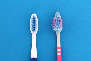  On a blue background are two toothbrushes, one old, used and the other new