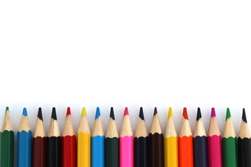 Bright colored pencils lie on a white background with space for text.