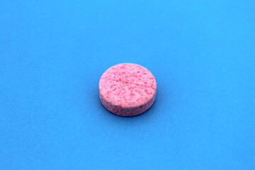 There is a pink pill on a blue background.