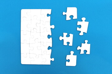 The game, a lot of white puzzle pieces lie on a blue background.	