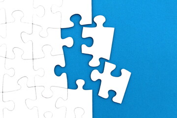 The game, a lot of white puzzle pieces lie on a blue background.