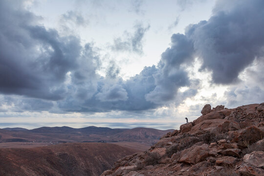 Photographer's silhouette in a rocky mountainous landscape with very dramatic sky in Fuerteventura, Canary Islands