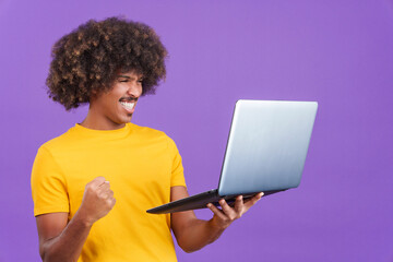 African man with curly hair celebrating while using a laptop