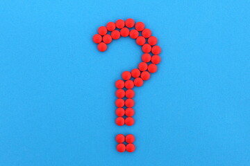 Of the red medicine pills lined with a question mark on a blue background.