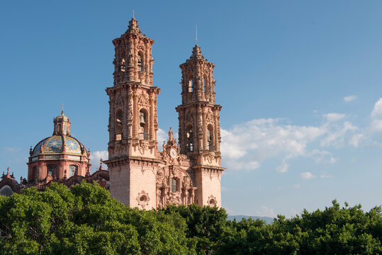 Taxco Cathedral's towers against a blue sky.