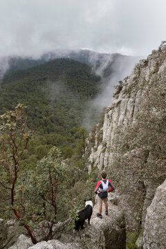 Man with his dog standing on the top of a rock looking at the landscape, Rancho Santa Elena, Hidalgo, Mexico