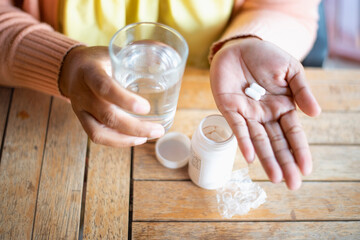 oung Asian woman holding pills in hand preparing for use The concept of taking care of one's health and helping people in the house.