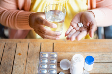 oung Asian woman holding pills in hand preparing for use The concept of taking care of one's health and helping people in the house.
