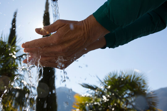 Low angle view of hands cupping splashing water in sun