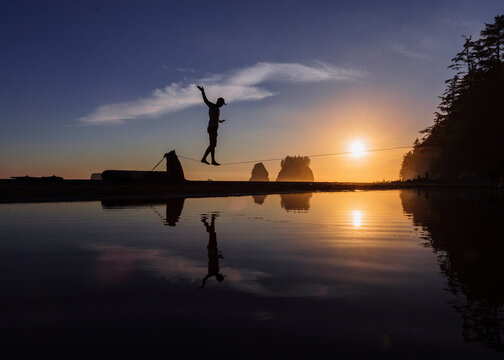 Slackliner walking over coastal water, La Push, Washington, USA