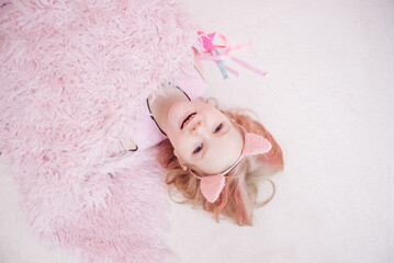 blonde girl with pink ears lies on the pink floor