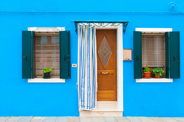 Blue facade of the house with door and windows. Burano, Italy.