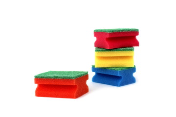  Many bright multi-colored sponges for washing dishes lie on a white background.