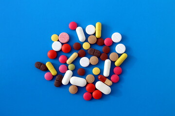 A pile of medicines of different sizes and colors lies on a blue background.