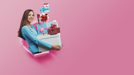 Happy young woman holding many gifts