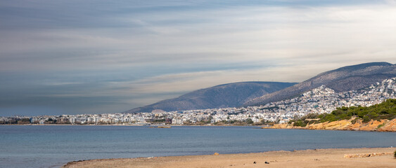 Athens, Greece. Panoramic view from Kavouri sandy beach of city building in front of mountain.