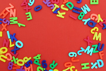 Background of bright multi-colored plastic letters lying on a red background.