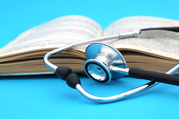 on a blue background lies a textbook with a stethoscope. medical education theme.	