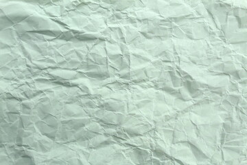 Soft crumpled sheet of light-colored paper. Abstract texture.	