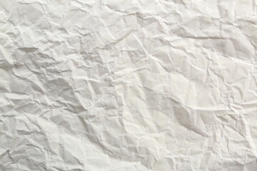 Soft crumpled sheet of light-colored paper. Abstract texture.	