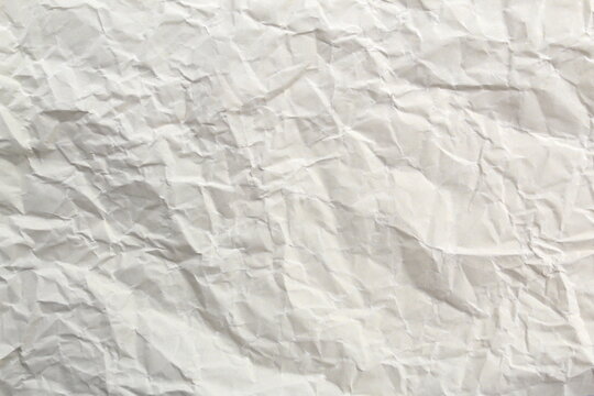 Soft crumpled sheet of light-colored paper. Abstract texture.	