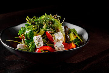Fresh greek salad with tomato, cucumber, bel pepper, olives and feta cheese in black bowl