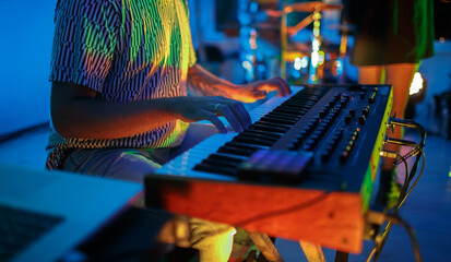 Pianist playing solo part with synthesizer piano on rock concert. Hands of professional musician...