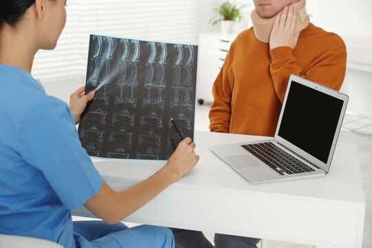 Doctor with neck MRI image consulting patient in clinic, closeup
