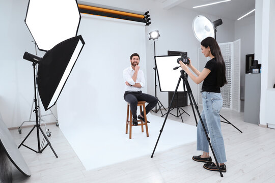 Professional photographer working with handsome model in modern photo studio