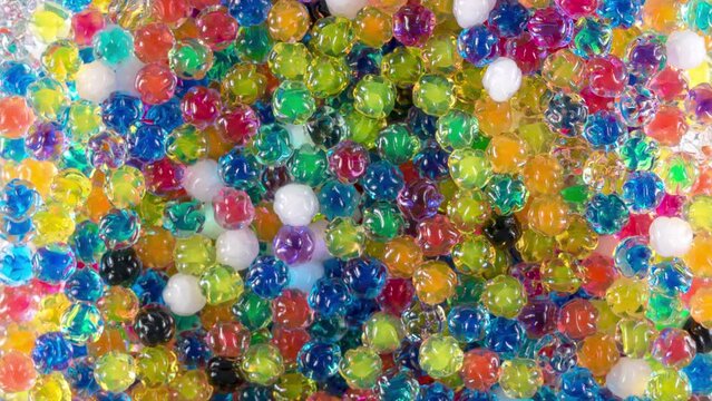 4K Time Lapse of Water beads growing in water close-up, abstract background, top view. Texture of Hydrogel jelly balls - many colorful beads.