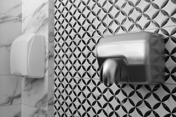 Hot air hand dryer on wall in public toilet
