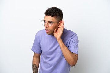 Fototapeta premium Young caucasian Brazilian man isolated on white background listening to something by putting hand on the ear