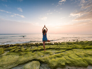 Fototapeta na wymiar woman doing yoga on tropical beach at sunset