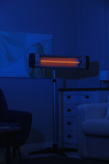 Electric infrared heater in dark living room at night