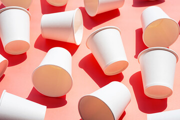 Several disposable white paper cups. Mock up to go coffee cups with shadows on pink.