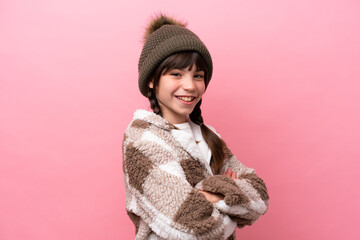 Little caucasian girl with winter jacket isolated on pink background with arms crossed and looking forward