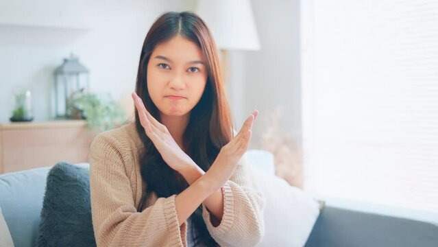 Upset Young asian woman showing prohibition sign crossing arms making refusal gesture negative shaking head dissatisfied serious, Female says no refuses demonstrates stop gesture