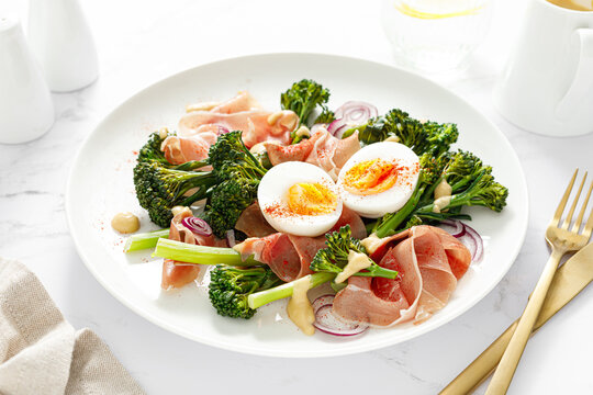 Easter egg salad with prosciutto and broccolini on white background. Easter salad with boiled egg
