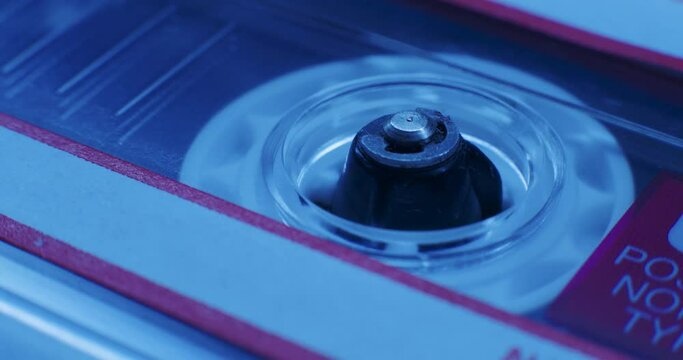Close-Up Of Cassette Tape Reel Turning In Blue Light