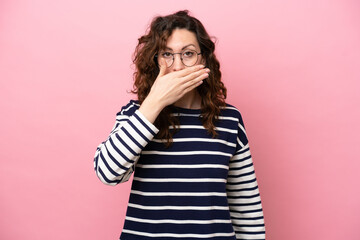 Young caucasian woman isolated on pink background covering mouth with hand