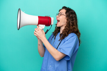Young nurse caucasian woman isolated on blue background shouting through a megaphone