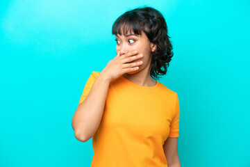 Young Argentinian woman isolated on blue background doing surprise gesture while looking to the side