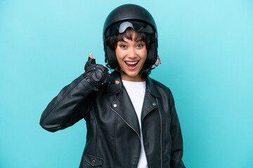 Young Argentinian woman with a motorcycle helmet isolated on blue background making phone gesture. Call me back sign