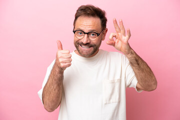 Middle age caucasian man isolated on pink background With glasses and doing OK sign