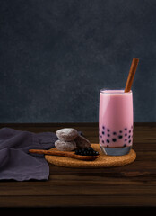 Strawberry bubble tea with strawberry mochi and tapioka pearls on a dark background.