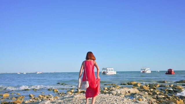 Woman in red dress running to the Baltic sea and impressed with the nature. 4k footage UHD 3840x2160 