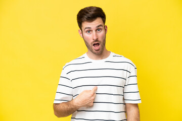 Young caucasian man isolated on yellow background pointing to oneself