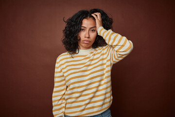 Young colombian curly hair woman isolated on brown background tired and very sleepy keeping hand on...